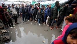 Palestinian refugees in line for food in the rain outside the shelter in Deir al-Balah (Photo: UNRWA)