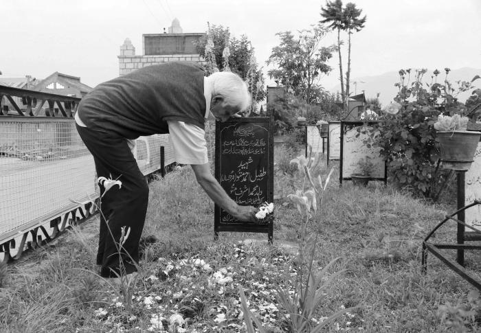 (Mohammad Ashraf Mattoo places flowers over the grave of Tufail Mattoo on his 10th death anniversary at Shaheed Marguzar (Martyrâs graveyard) in Srinagar on June 11, 2020). Picture: Kamran Yousuf/NewsClick