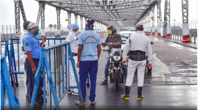 Police personnel stop commuters at Howrah Bridge, during the complete biweekly lockdown in the wake of coronavirus pandemic, in Kolkata. | Photo Credit: PTI