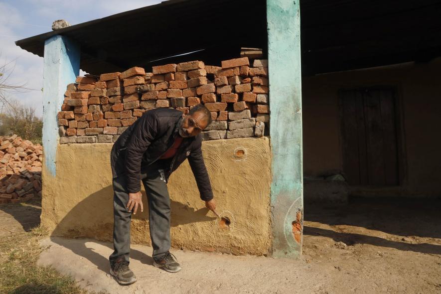 A resident pointing out a house in the Dangri village that has bullet hole(Photo by Kamran Yousuf).